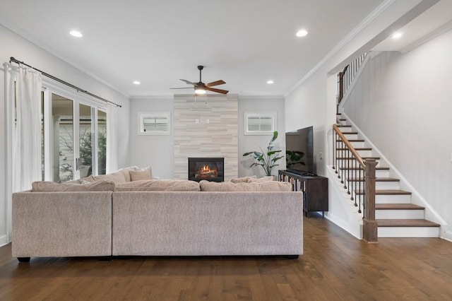 living area featuring dark wood-style flooring, ornamental molding, stairs, and ceiling fan