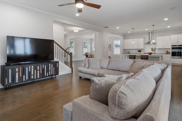 living area with stairs, ceiling fan, ornamental molding, and dark wood-style flooring