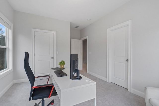 office area featuring baseboards, visible vents, and light colored carpet