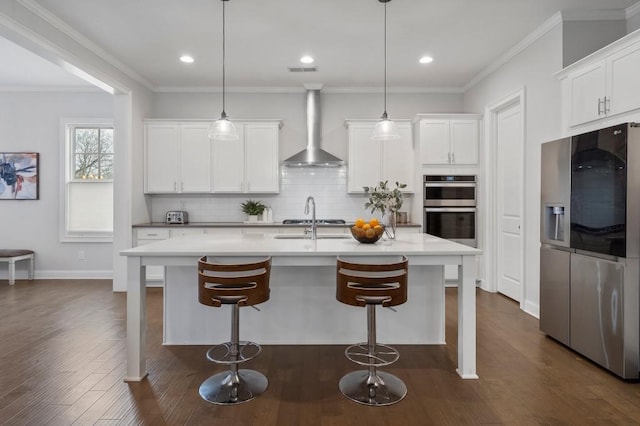 kitchen featuring white cabinetry, wall chimney range hood, stainless steel appliances, and tasteful backsplash