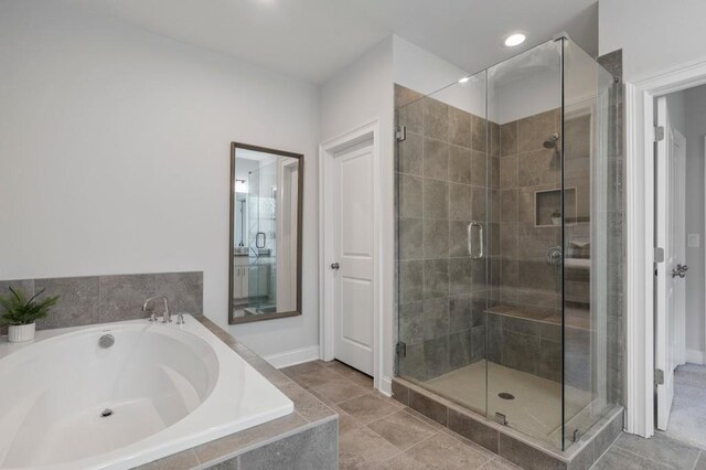 bathroom featuring tile patterned floors, a stall shower, and a garden tub