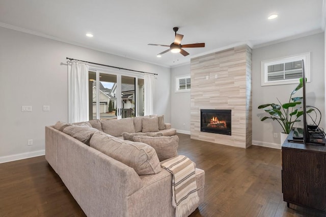 living room featuring crown molding, a tile fireplace, a ceiling fan, and dark wood finished floors