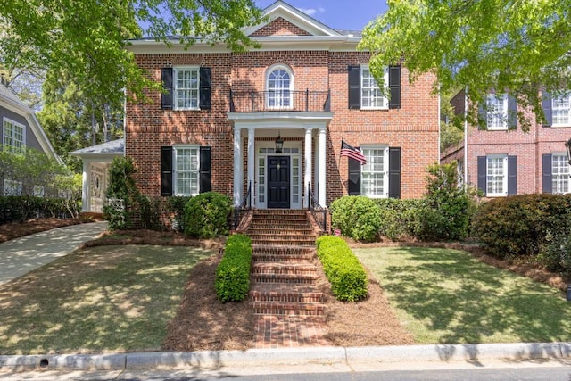 colonial inspired home with brick siding and a front lawn