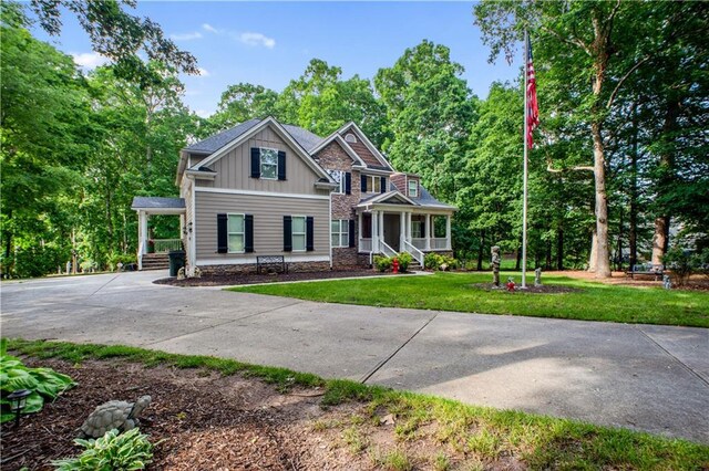 261 Double Springs Rd SW, Monroe, GA 30656 - view of front of property featuring board and batten siding, covered porch, driveway, a front yard, and view of scattered trees