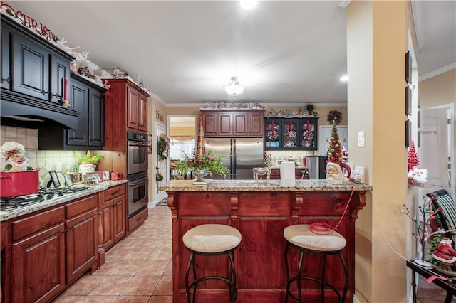 261 Double Springs Rd SW, Monroe, GA 30656 - kitchen featuring appliances with stainless steel finishes, ornamental molding, tasteful backsplash, a kitchen bar, and light stone countertops