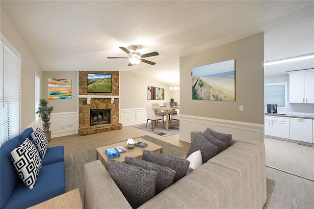 living room featuring ceiling fan, a fireplace, light hardwood / wood-style floors, and lofted ceiling