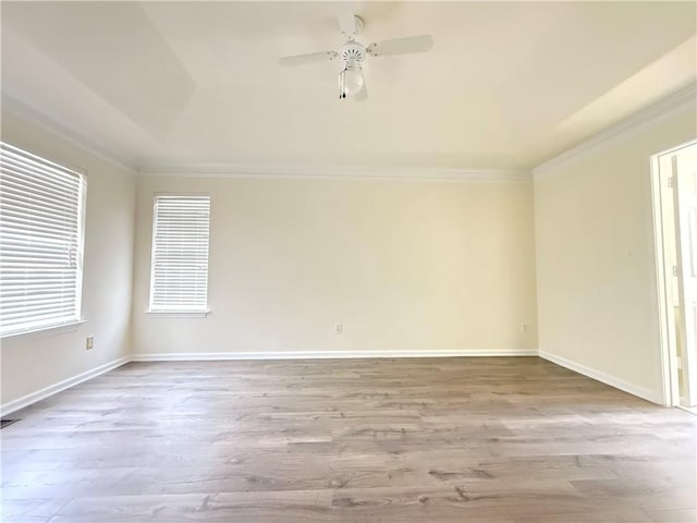 spare room featuring wood finished floors, a ceiling fan, baseboards, and ornamental molding