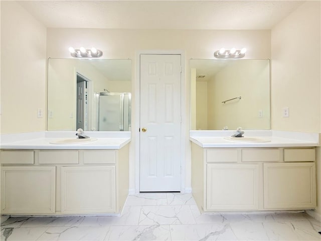 full bath featuring marble finish floor, a stall shower, and a sink