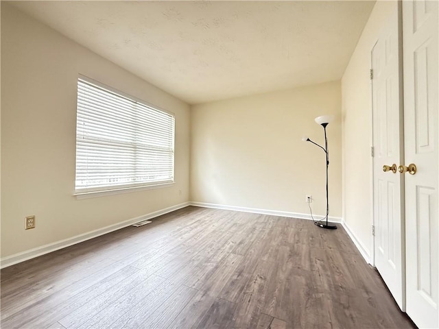 empty room with visible vents, baseboards, and dark wood finished floors