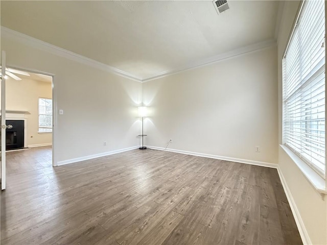 unfurnished room featuring baseboards, visible vents, a fireplace, dark wood-type flooring, and crown molding