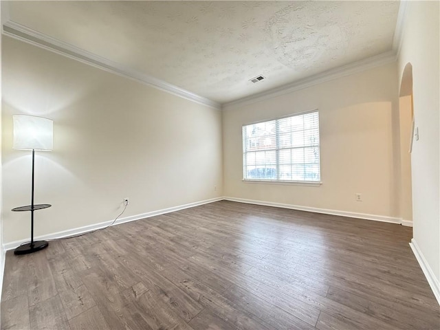 unfurnished room featuring dark wood-type flooring, baseboards, visible vents, and ornamental molding