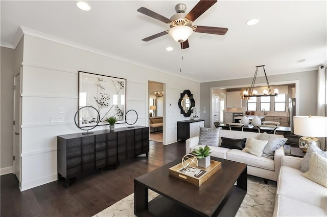 living room featuring ceiling fan with notable chandelier, dark hardwood / wood-style floors, and ornamental molding