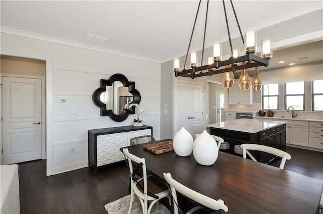 dining area featuring dark hardwood / wood-style floors, crown molding, and sink