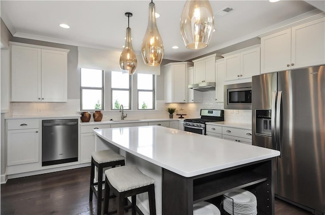 kitchen with sink, dark hardwood / wood-style floors, pendant lighting, a kitchen island, and appliances with stainless steel finishes