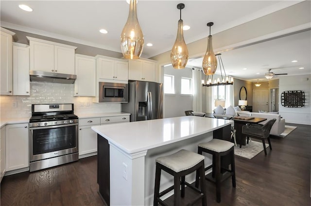 kitchen featuring appliances with stainless steel finishes, a center island, dark hardwood / wood-style floors, and ceiling fan