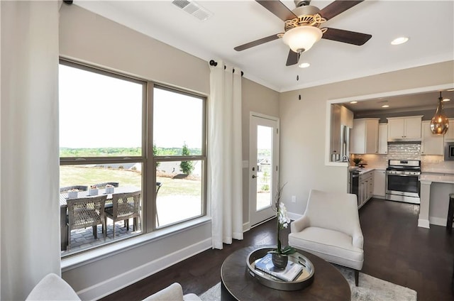 living area featuring ceiling fan, dark hardwood / wood-style floors, and ornamental molding