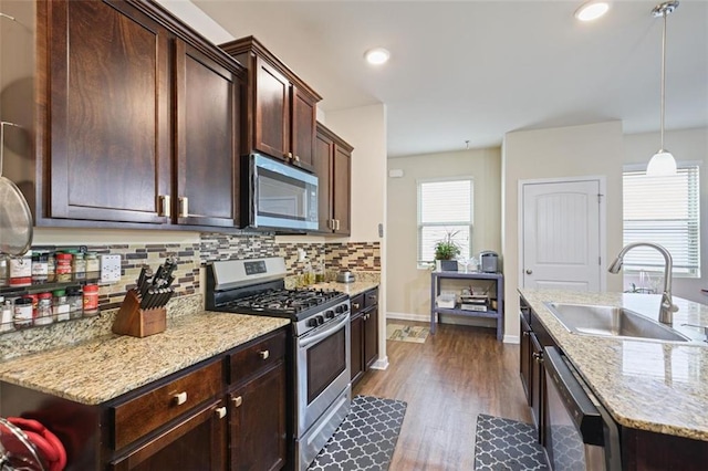 kitchen with dark brown cabinetry, decorative backsplash, dark wood-style floors, stainless steel appliances, and a sink