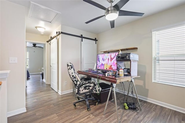 office featuring a barn door, baseboards, wood finished floors, and a ceiling fan