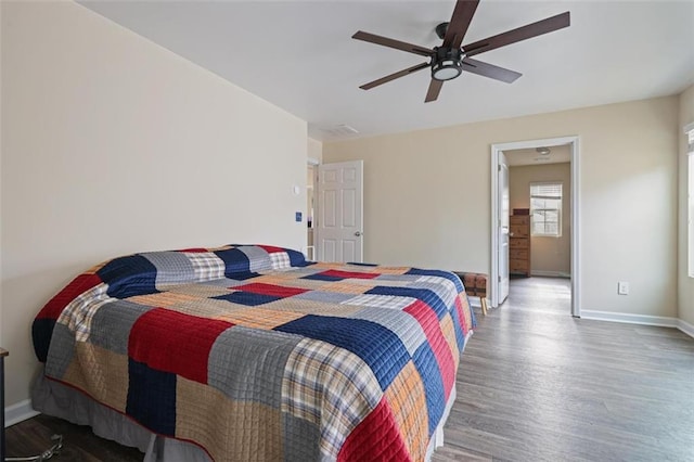 bedroom with a ceiling fan, wood finished floors, and baseboards