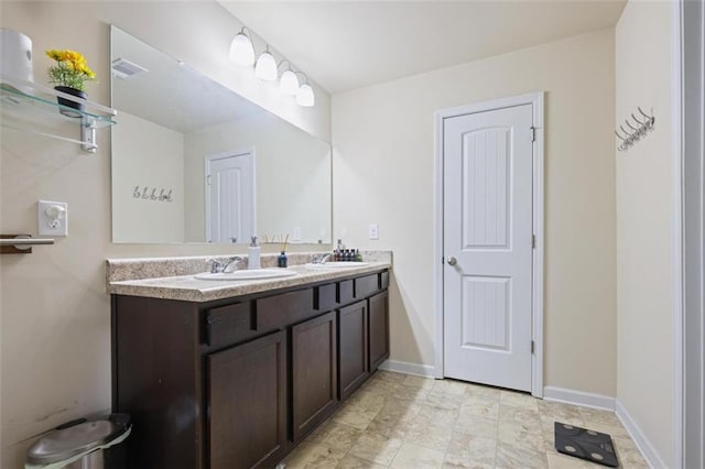 bathroom featuring double vanity, visible vents, baseboards, and a sink