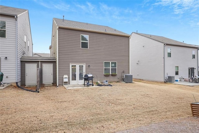 rear view of house featuring central air condition unit, a lawn, french doors, and a patio