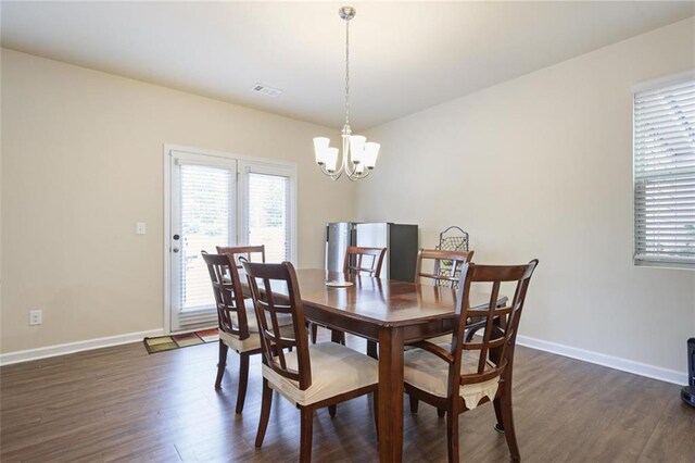 dining area with visible vents, plenty of natural light, an inviting chandelier, and dark wood finished floors