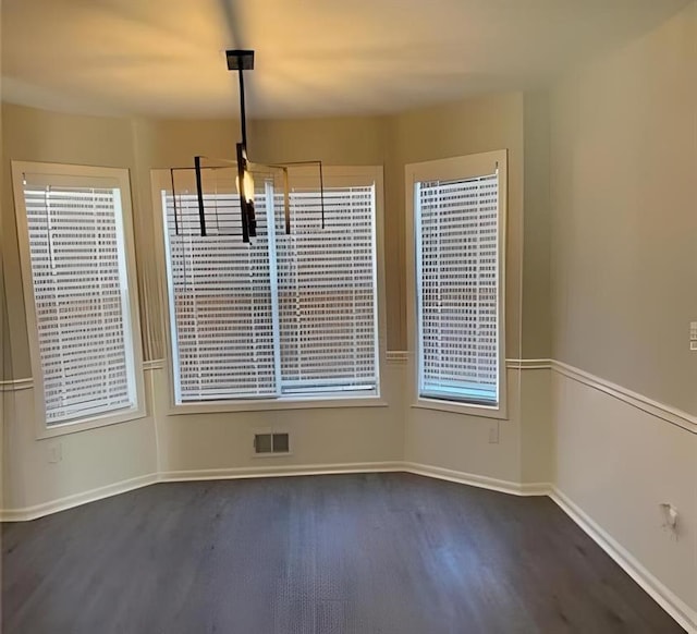 unfurnished dining area with visible vents, baseboards, and dark wood-style flooring