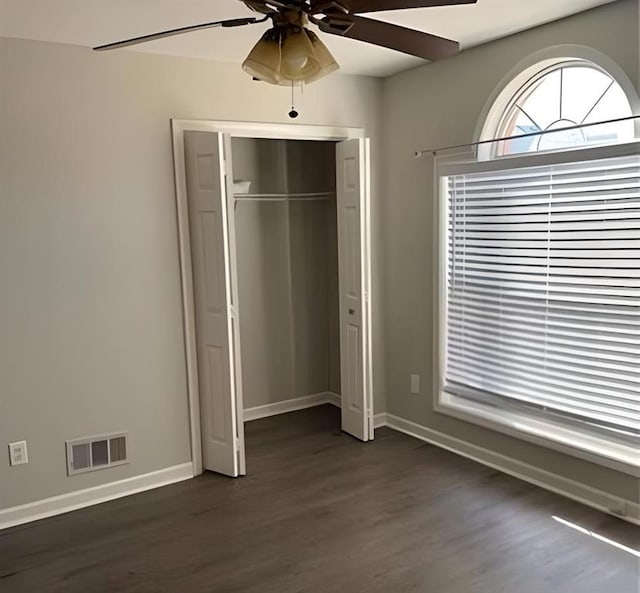 unfurnished bedroom featuring visible vents, baseboards, a closet, dark wood-style floors, and a ceiling fan