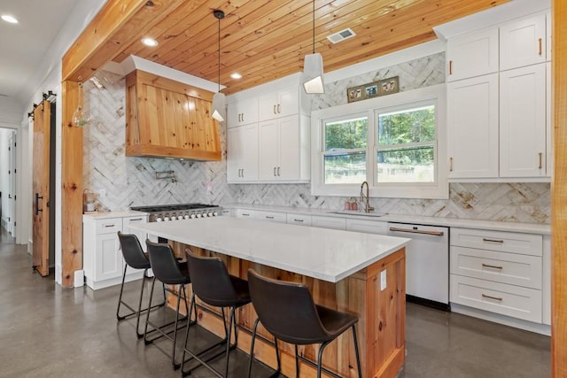 kitchen featuring a kitchen island, pendant lighting, white cabinetry, dishwasher, and a barn door