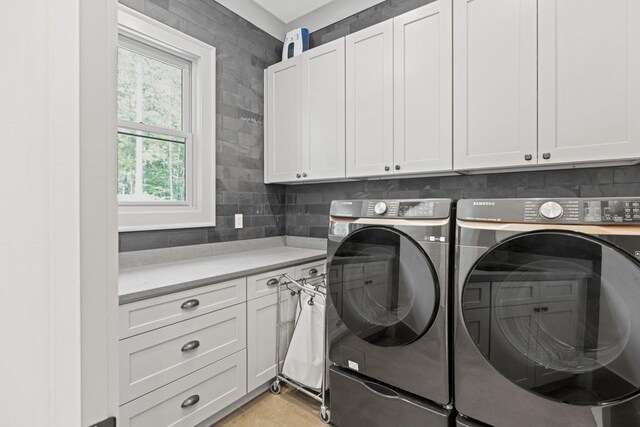 laundry room with separate washer and dryer and cabinets