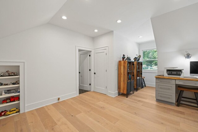 office area with lofted ceiling, light wood-type flooring, and built in shelves