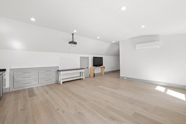 bonus room with a wall mounted air conditioner, vaulted ceiling, and light wood-type flooring