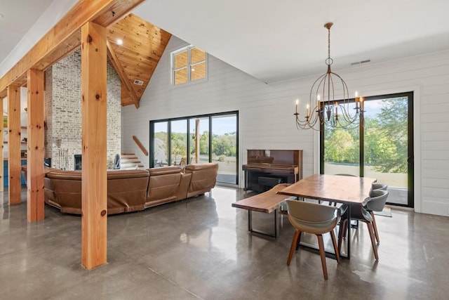 dining room featuring an inviting chandelier, concrete flooring, and high vaulted ceiling