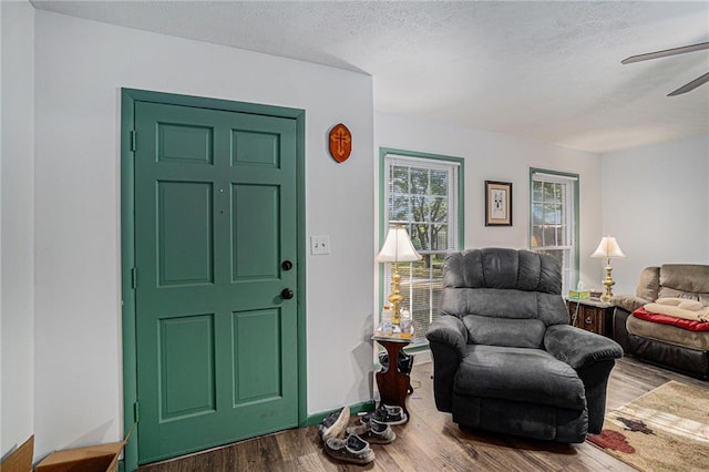 interior space with ceiling fan, a textured ceiling, and hardwood / wood-style floors