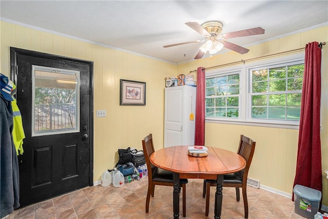 dining area featuring ornamental molding, wooden walls, and ceiling fan