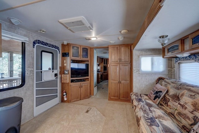 kitchen featuring wallpapered walls, glass insert cabinets, visible vents, and brown cabinets