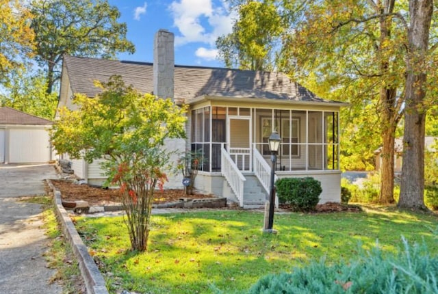 bungalow-style house with a sunroom and a front lawn