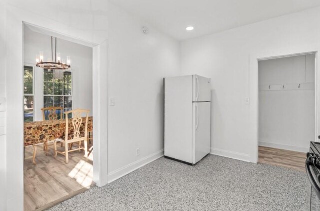 bedroom with hardwood / wood-style flooring, white refrigerator, and a chandelier