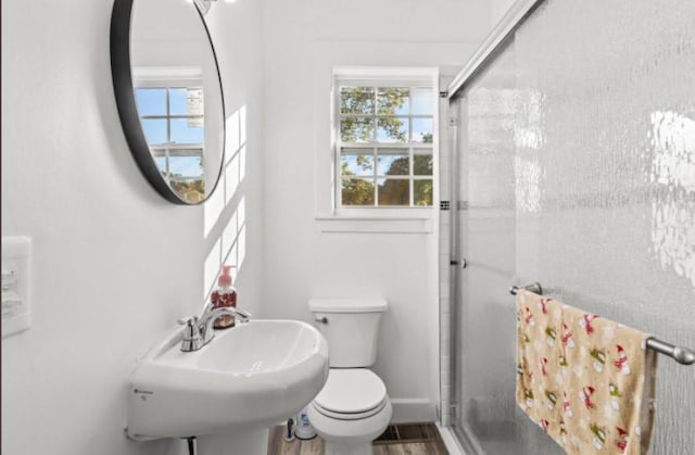 bathroom with a wealth of natural light, toilet, an enclosed shower, and hardwood / wood-style flooring