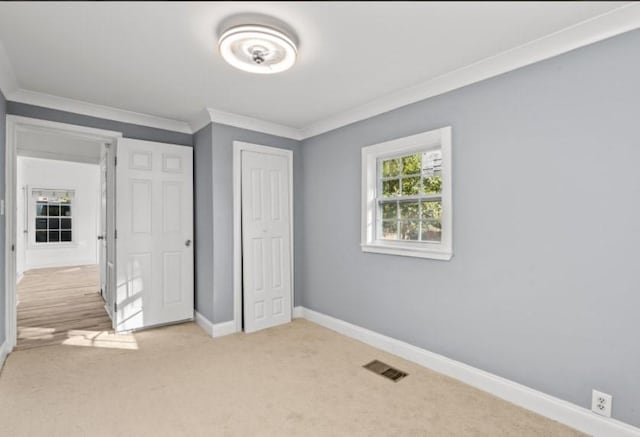 unfurnished bedroom with light colored carpet, ornamental molding, and a closet