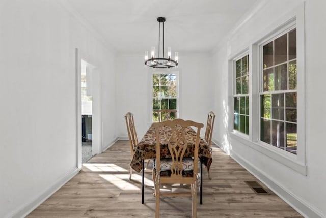 dining space with a chandelier, crown molding, and light hardwood / wood-style flooring