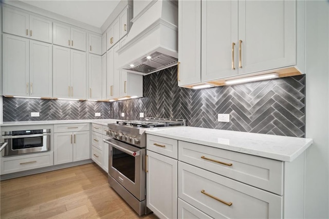 591 Brashy St, Woodstock, GA 30188 - kitchen with appliances with stainless steel finishes, custom range hood, light stone countertops, decorative backsplash, and light wood-style floors