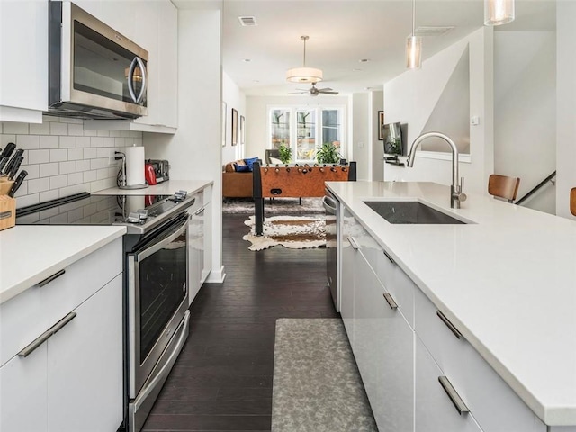 415 Gartrell St SE Unit 16, Atlanta, GA 30312 - kitchen featuring appliances with stainless steel finishes, backsplash, white cabinets, dark wood-style floors, and open floor plan