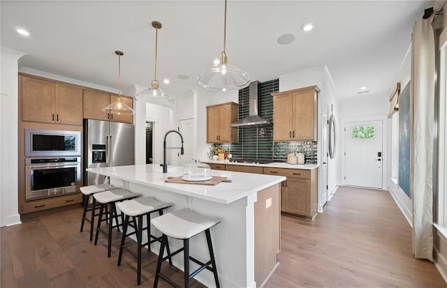 kitchen featuring decorative backsplash, wall chimney exhaust hood, a breakfast bar area, stainless steel appliances, and light countertops