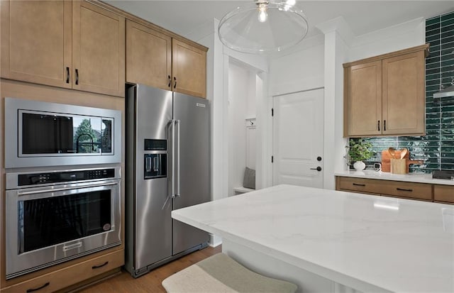 kitchen featuring light stone counters, crown molding, decorative backsplash, appliances with stainless steel finishes, and wood finished floors