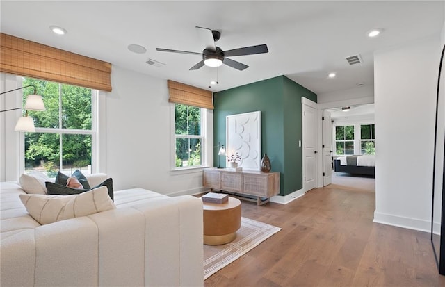 interior space with ceiling fan, wood finished floors, visible vents, and baseboards