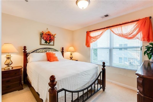 bedroom featuring baseboards, visible vents, and light colored carpet