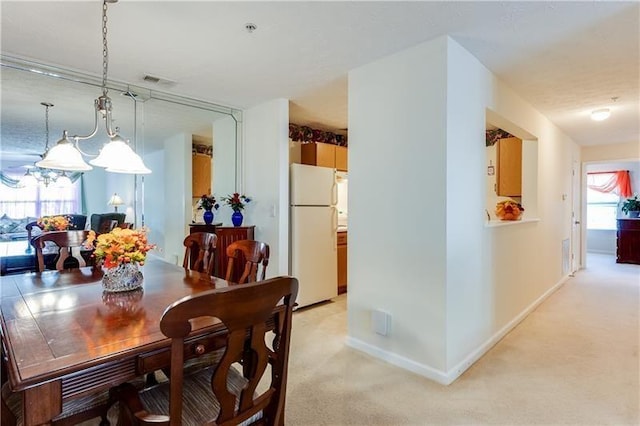dining room with a notable chandelier, light colored carpet, and baseboards