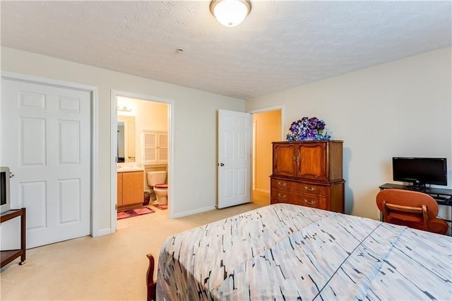 bedroom featuring baseboards, ensuite bathroom, and light carpet