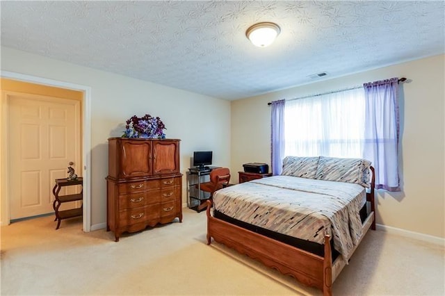 bedroom with baseboards, light carpet, a textured ceiling, and visible vents